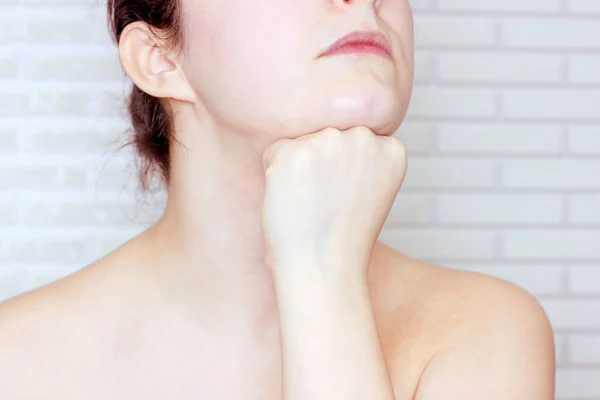 Young caucasian woman touching her face with hands doing face fitness exercises. Facial lifting and massage concept.