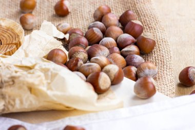 Tahta üzerinde kahverengi fındıklar ve tekstil arka planı..