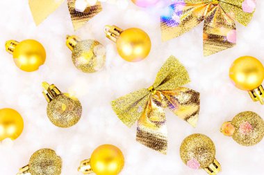 Parlak altın Xmas dekorasyonlarının (kurdeleler, takılar, yaylar, süsler) üst görünümü beyaz yapay kar arka planında yatıyordu. Noel ve Yeni Yıl Geleneksel Bayram Kutlaması.