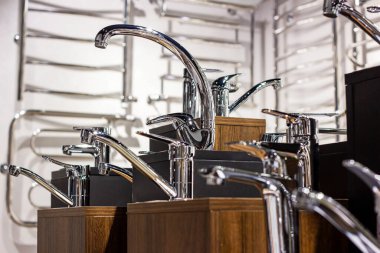 Mağaza vitrinindeki banyo için yeni modern metal su muslukları koyu arka planda duruyor..