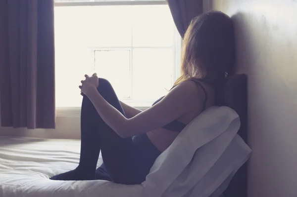 Young woman sitting on bed in the morning — Stock Photo, Image