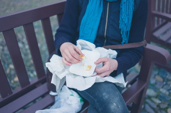 Молодая женщина с оберточной бумагой на скамейке — стоковое фото