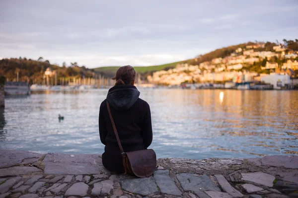 Jeune femme assise au bord de l'eau dans une petite ville — Photo