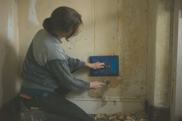 Young woman removing wallpaper