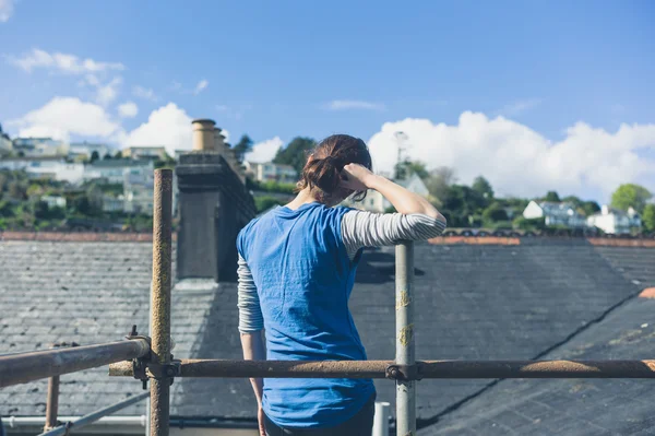Young woman on scaffolding by roof — Stock Photo, Image