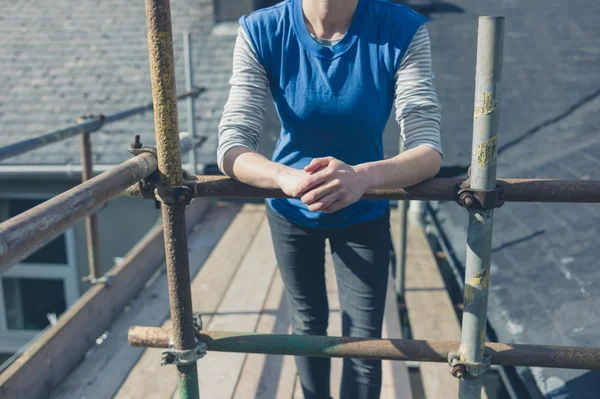 Young woman on scaffolding by roof — Stock Photo, Image