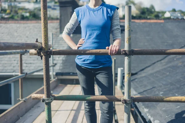 Young woman on scaffolding by roof — Stock Photo, Image