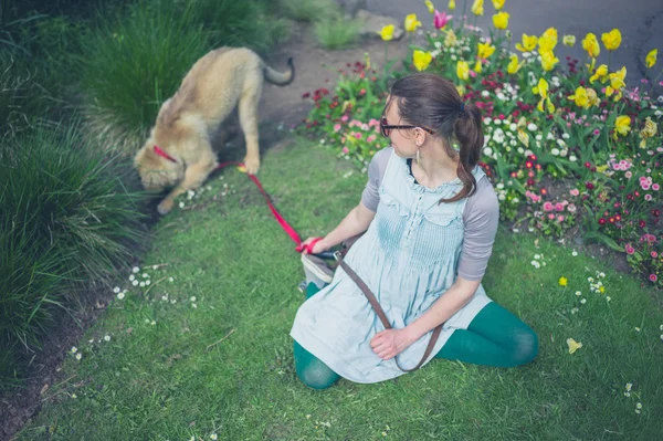 Jovem sentada na grama com filhote de cachorro — Fotografia de Stock