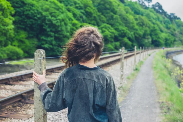 一个年轻女子站在铁轨旁 — 图库照片