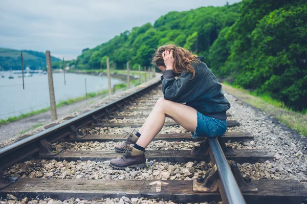一个悲伤的年轻女子坐在铁轨上 — 图库照片