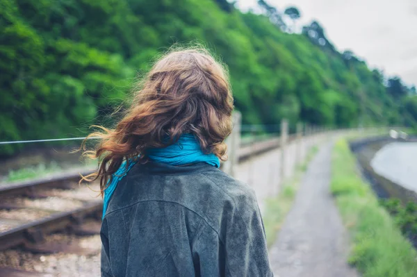 水の体の近くの線路で若い女性が立っています — ストック写真