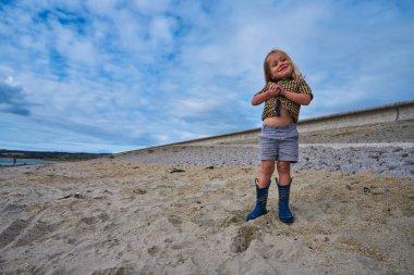 Küçük bir anaokulu öğrencisi yazın plajda oynuyor.