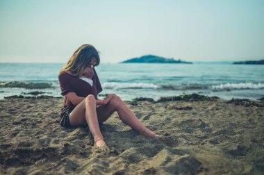 Yavrusu askıda, kumsalda dinlenen genç bir anne.