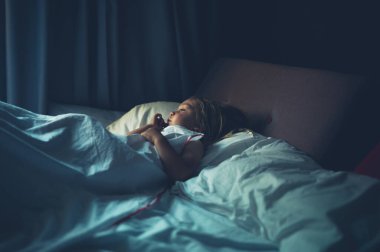 Küçük bir anaokulu öğrencisi sabah yatağında yatıyor.