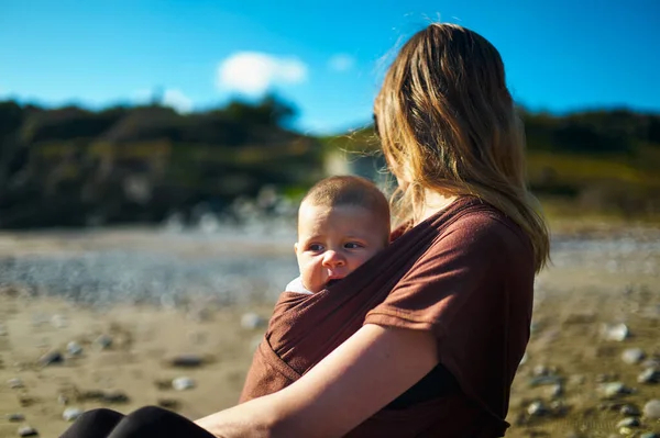 一位年轻的母亲带着她的孩子坐在海滩上 — 图库照片