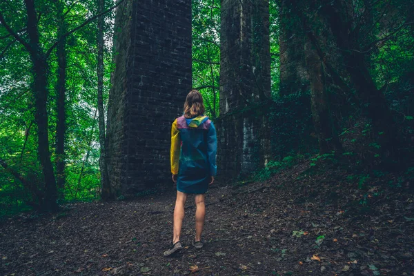 レインコートを着た若い女性が秋に森の中を歩いている — ストック写真