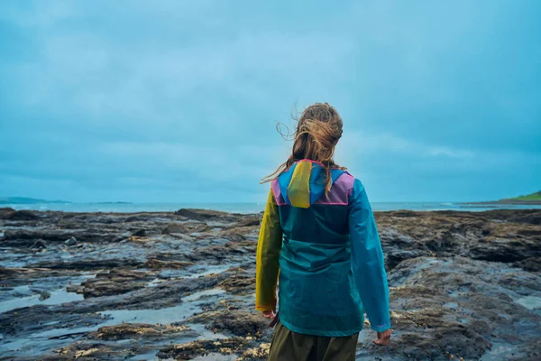 一位穿着雨衣的年轻女子站在海边 — 图库照片