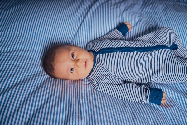 Ένα Μικρό Μωρό Ένα Ριγέ Romper Βρίσκεται Ταιριάζουν Κρεβάτι — Φωτογραφία Αρχείου