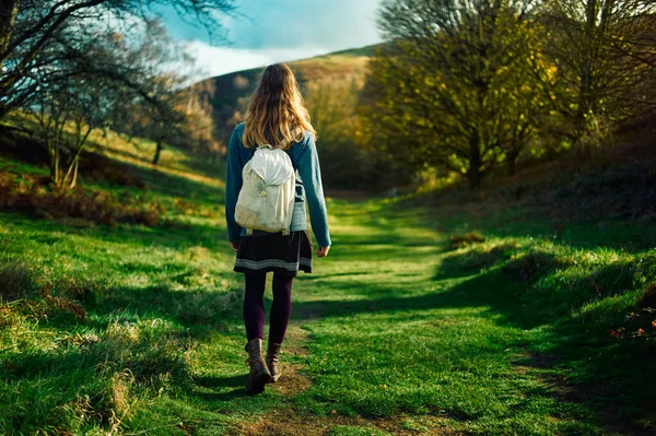 在一个阳光明媚的秋日 一位年轻女子正在草地和林地里散步 — 图库照片