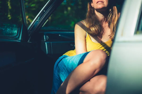 晴れた日にドアが開いている車の中で若い女性が休んでいる — ストック写真