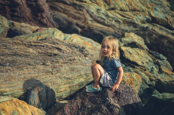 Küçük Bir Anaokulu Öğrencisi Sahilde Kayalıklarda Oturuyor — Stok fotoğraf
