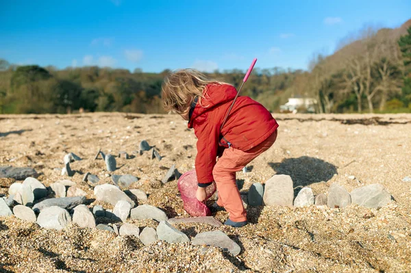 Küçük Bir Anaokulu Öğrencisi Kışın Sahilde Kayalarla Oynuyor Stok Fotoğraf