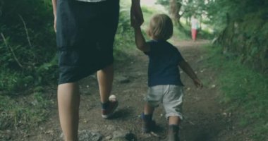 Küçük çocuk ve annesi ormanda yürüyor. 