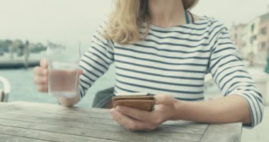 Kafede akıllı telefon ve içme suyu kullanan kadın, yakın çekim görüntüsü