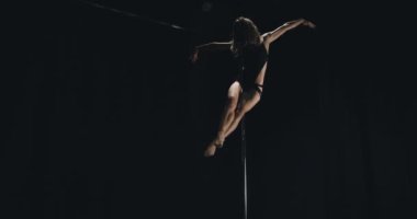 Karanlıkta dans eden siyah iç çamaşırlı seksi kadın. Kutup dansı konsepti.