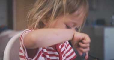 Çizgili tişörtlü şirin kız mutfakta yemek yiyor.