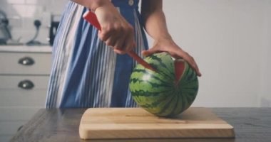 Evde karpuz kesen bir kadın.