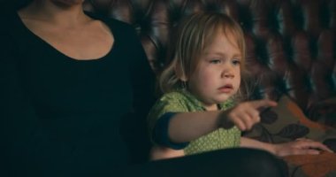 Küçük çocuk annesiyle televizyon izliyor.