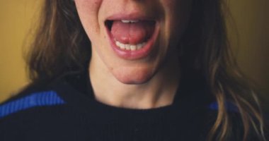 Dilini çıkaran belirsiz bir kadın yüzü.