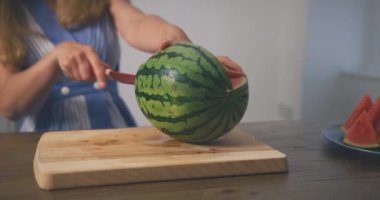 Evde karpuz kesen bir kadın.