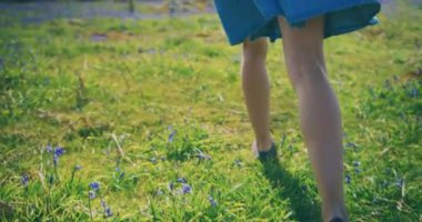 Yeşil alanda küçük çiçeklerle yürüyen dişi ayaklar.