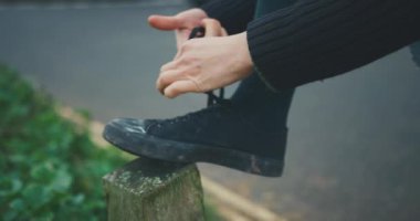 Ayakkabı bağcıklarını dışarıda bağlayan kişi