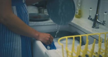 Kadın evinde bulaşık yıkıyor.