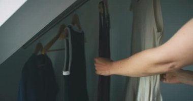 Kadın evde elbise seçiyor.