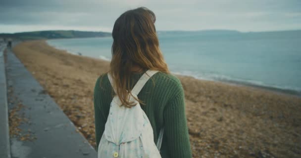 白いバックパックを着た若い美しい女性が海辺を見て — ストック動画