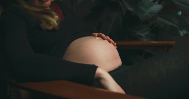 妊娠中の女性が部屋の木製の椅子に座り — ストック動画