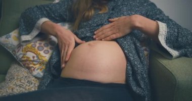 Kanepede oturan hamile kadın.