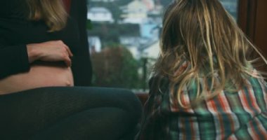 Hamile kadın oğluyla birlikte pencere eşiğinde oturuyor.