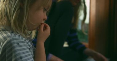 Anne ve küçük oğlu evde kitap okuyor.