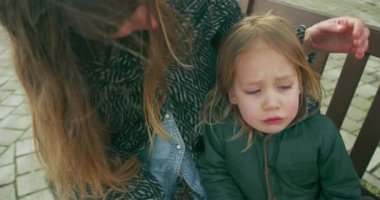 Anne ve küçük oğlu dışarıdaki tahta bankta oturuyor.