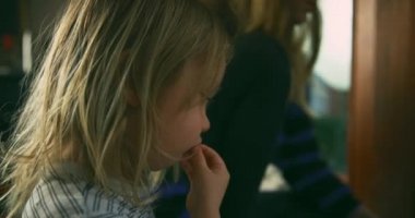 Anne ve küçük oğlu evde kitap okuyor.