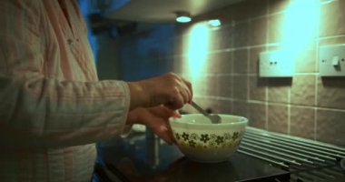 Kadın mutfakta çırpılmış yumurta pişiriyor.