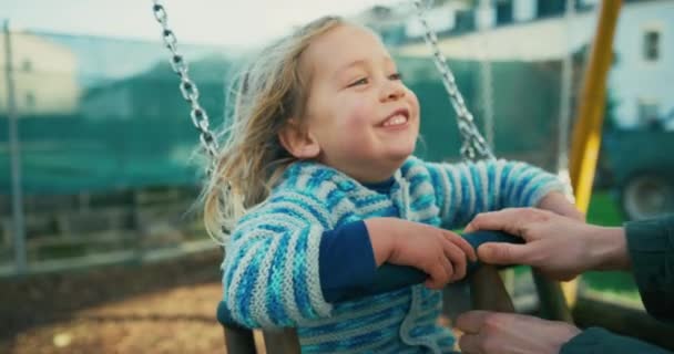 小さな笑顔の男の子が公園の遊び場で揺れています — ストック動画