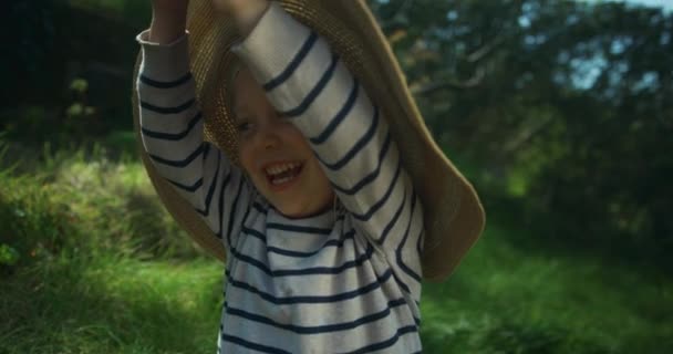 可爱的小男孩躲在花园里的帽子下 — 图库视频影像