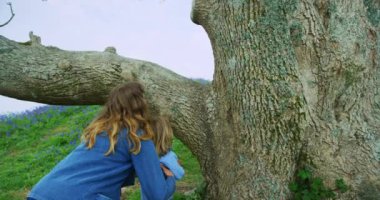 Kadın ve küçük oğlu açık havada ağaca tırmanıyorlar.