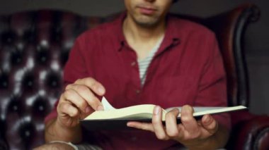 Adam evde kitap okuyor.